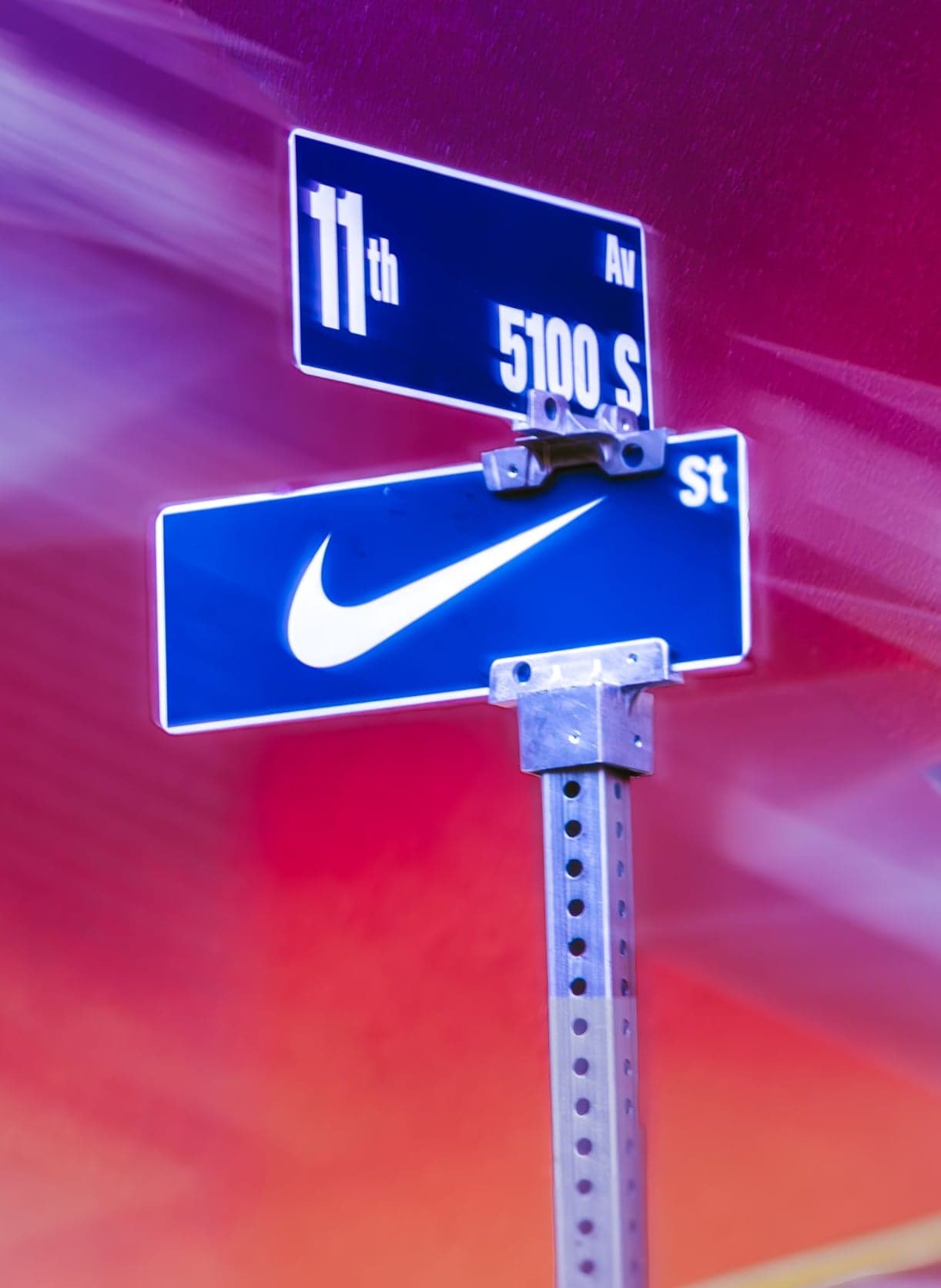 A Nike-branded 11th Ave street sign against a purple and pink canopy