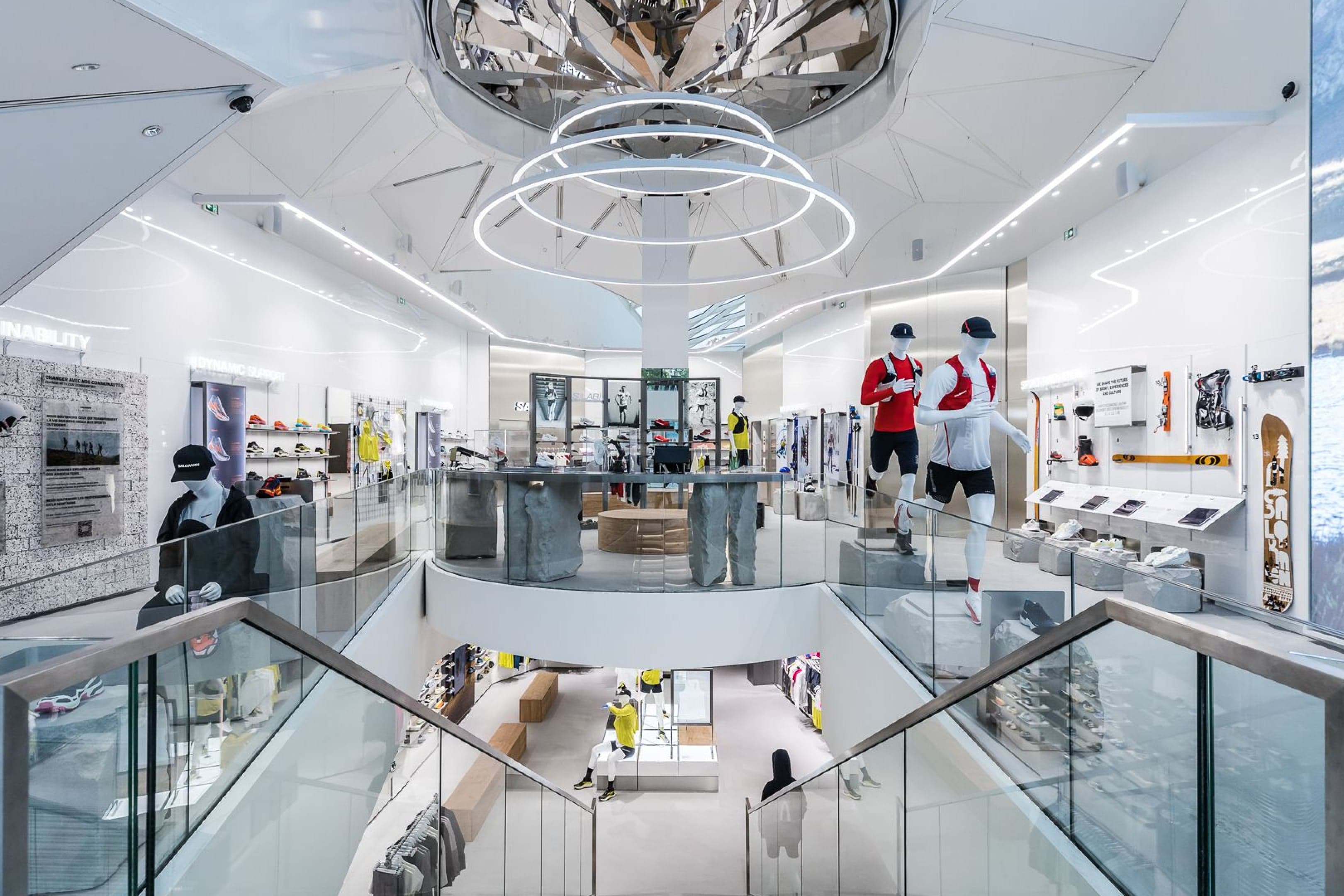 The store’s atrium, with a mirrored chandelier above glass-railed stairs and mannequins in running gear