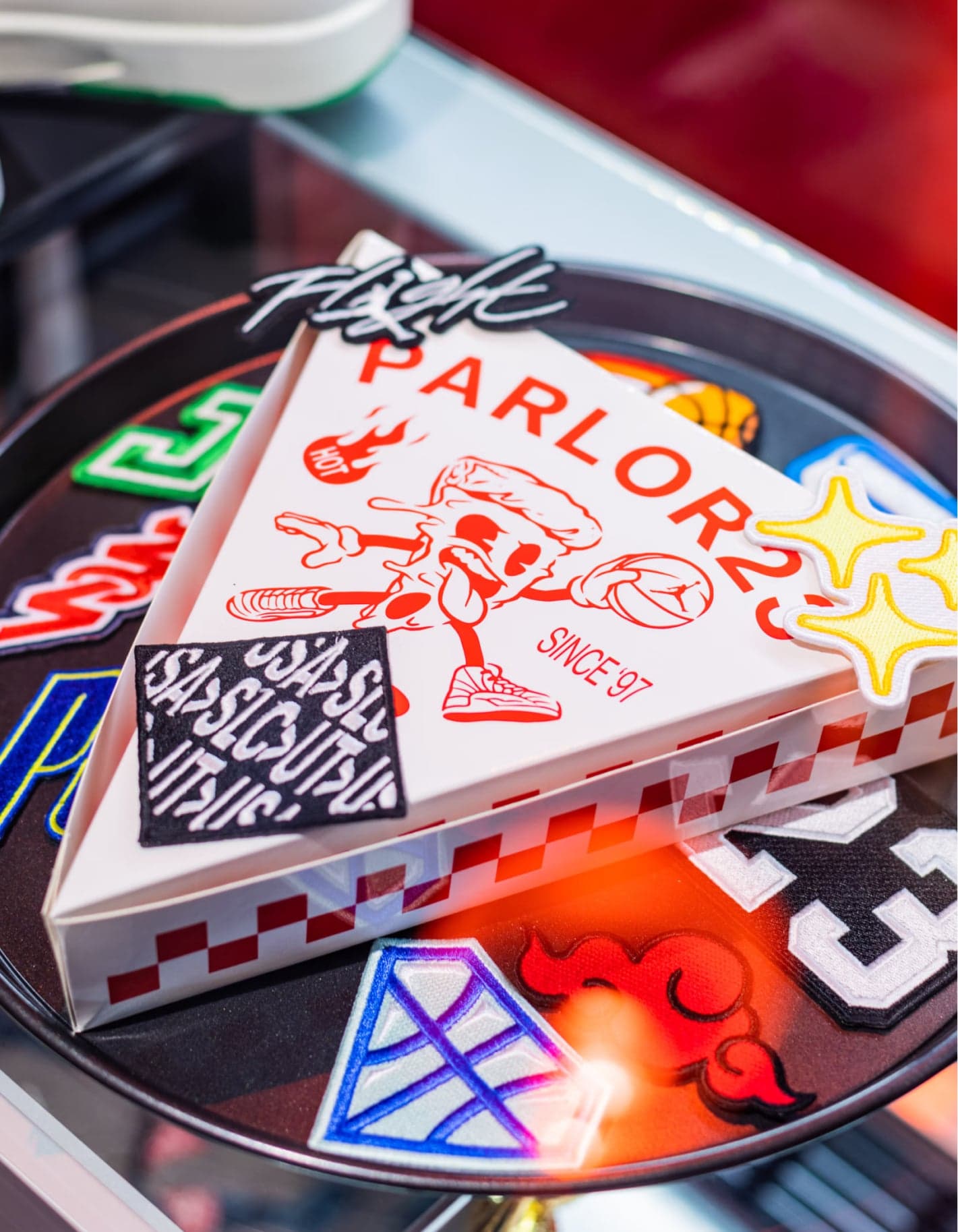 A Parlor 23 pizza box on a turntable covered in embroidered patches