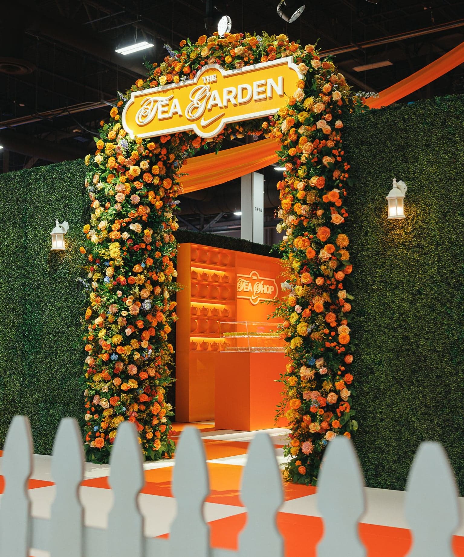 The floral Tea Garden arch above a white picket fence