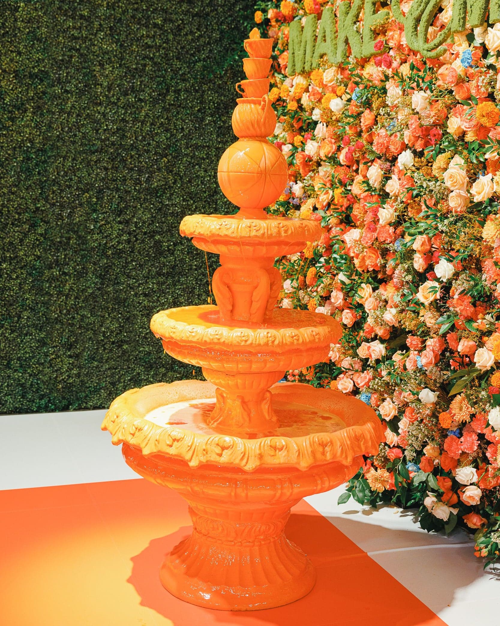 Close-up of the tiered orange fountain against a wall of flowers