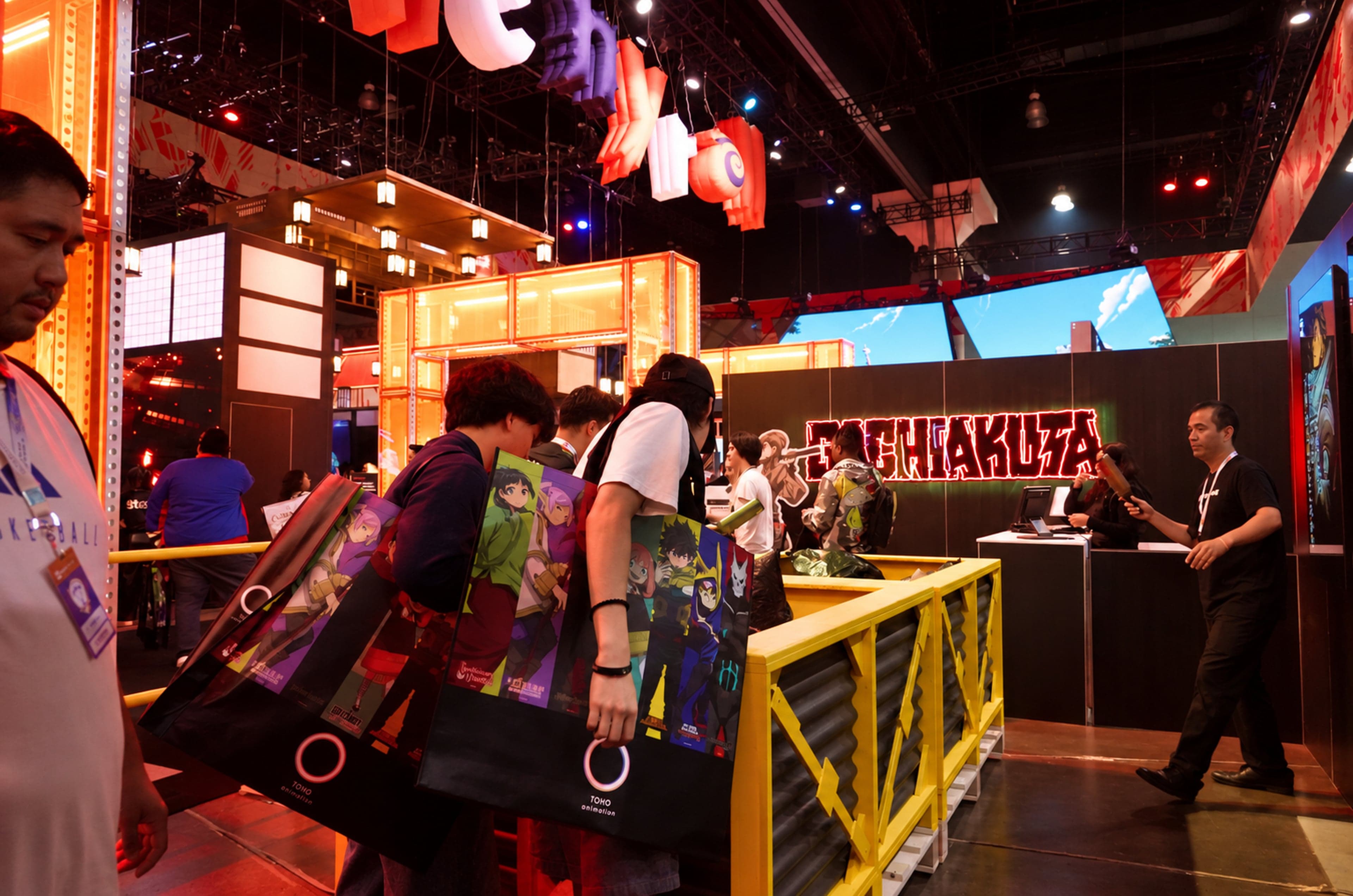 Fans with Crunchyroll tote bags at the yellow trash pit in front of the Gachiakuta wall