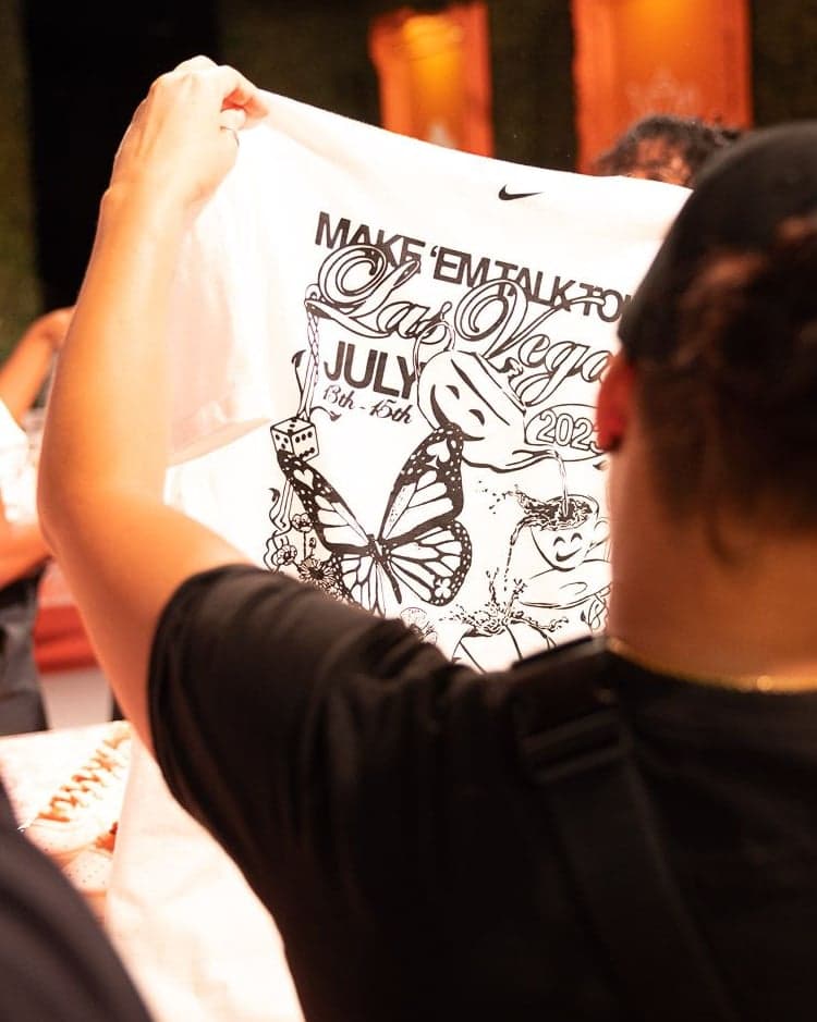 A guest holding up a freshly printed Make ’Em Talk tee