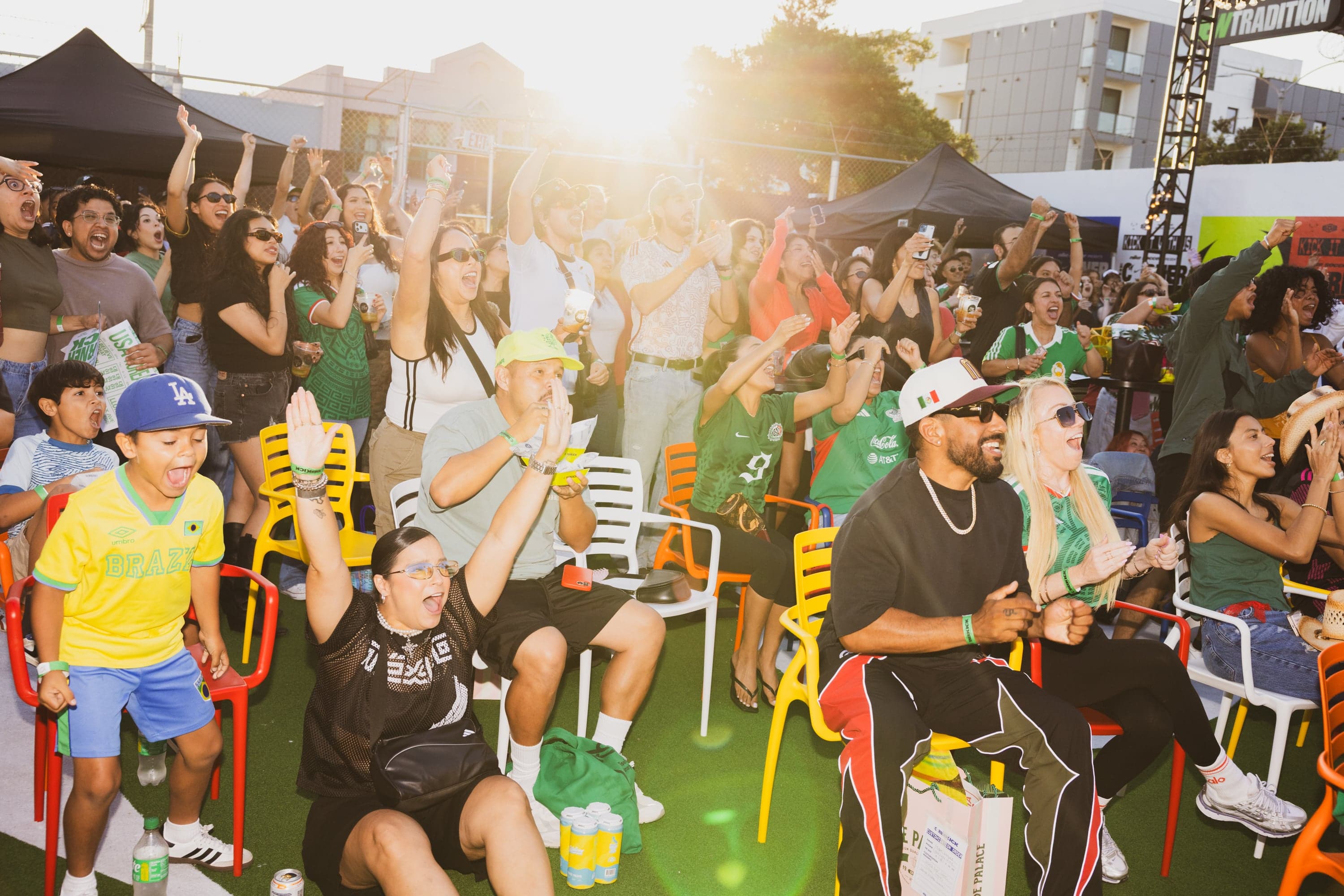 A crowd watching a World Cup match in the sunlit back lot