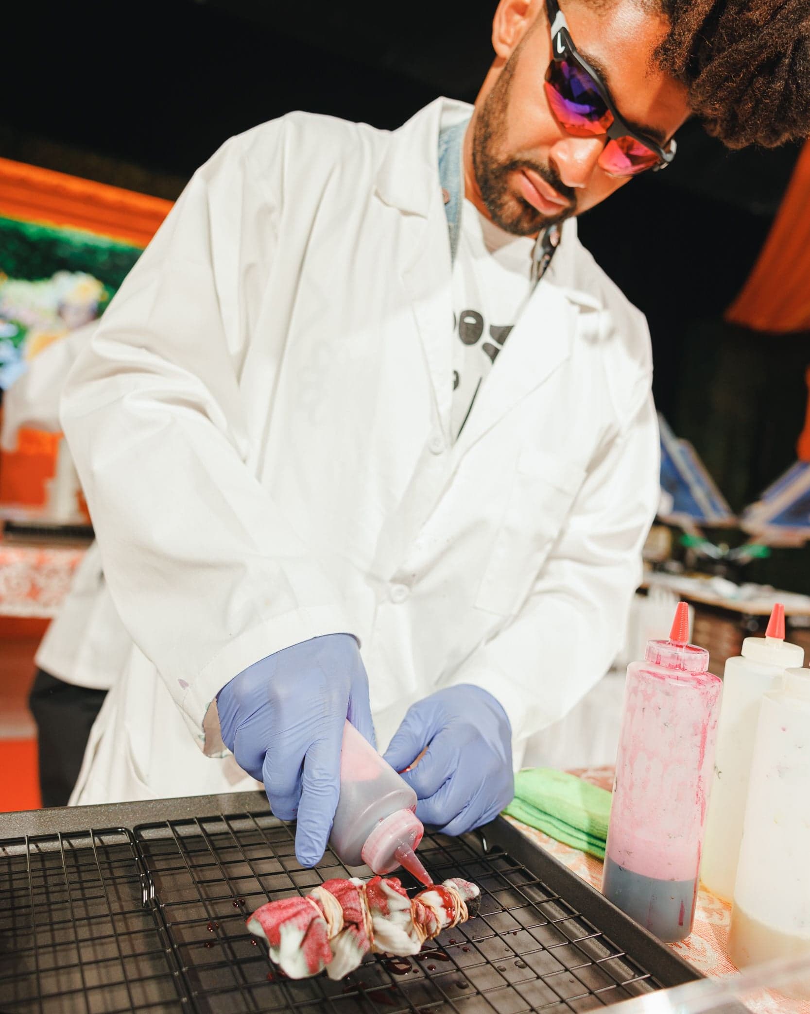 A staff member in a lab coat and gloves preparing custom apparel