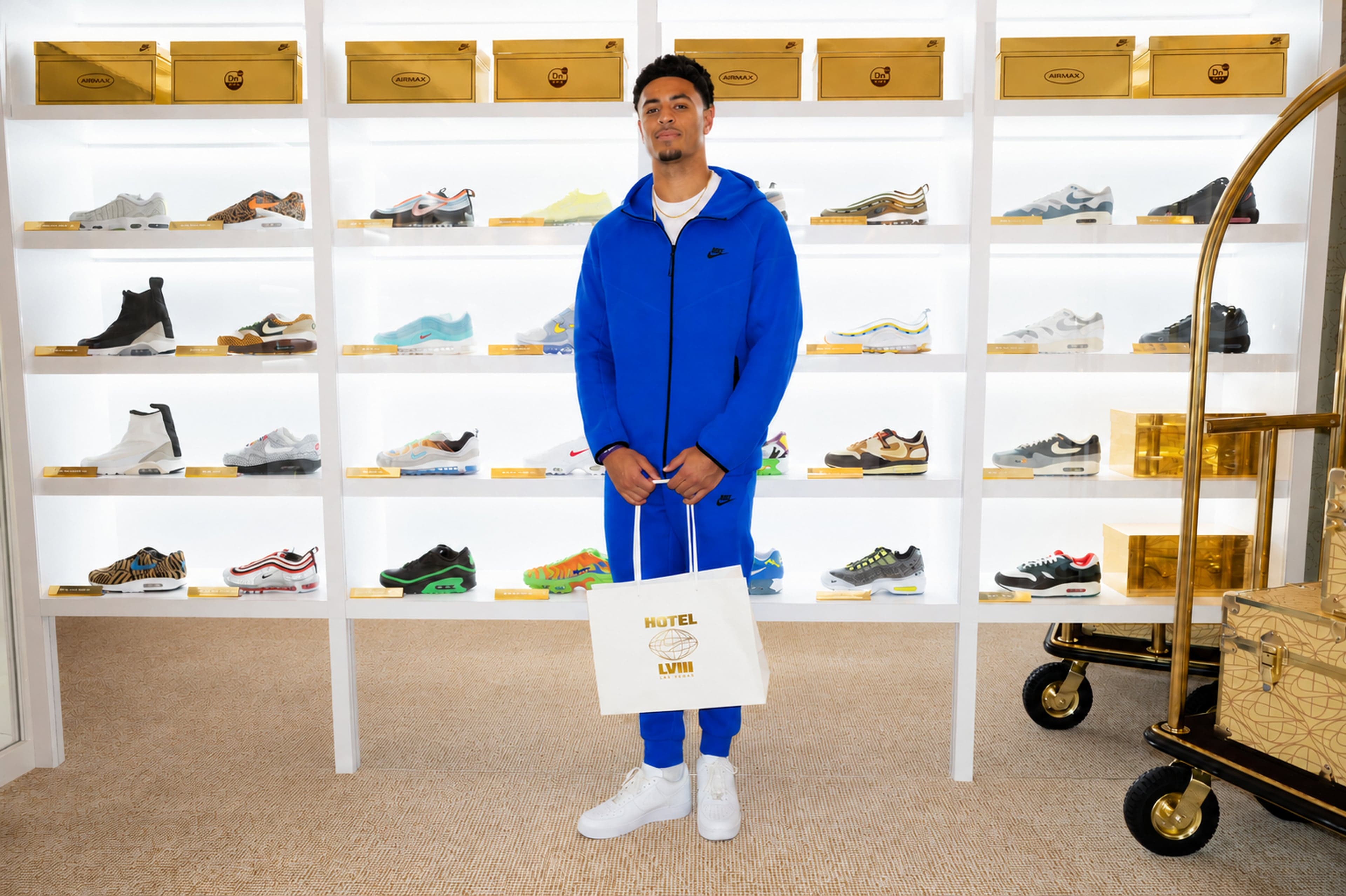 A guest holding a Hotel LVIII tote in front of the Air Max shoe wall