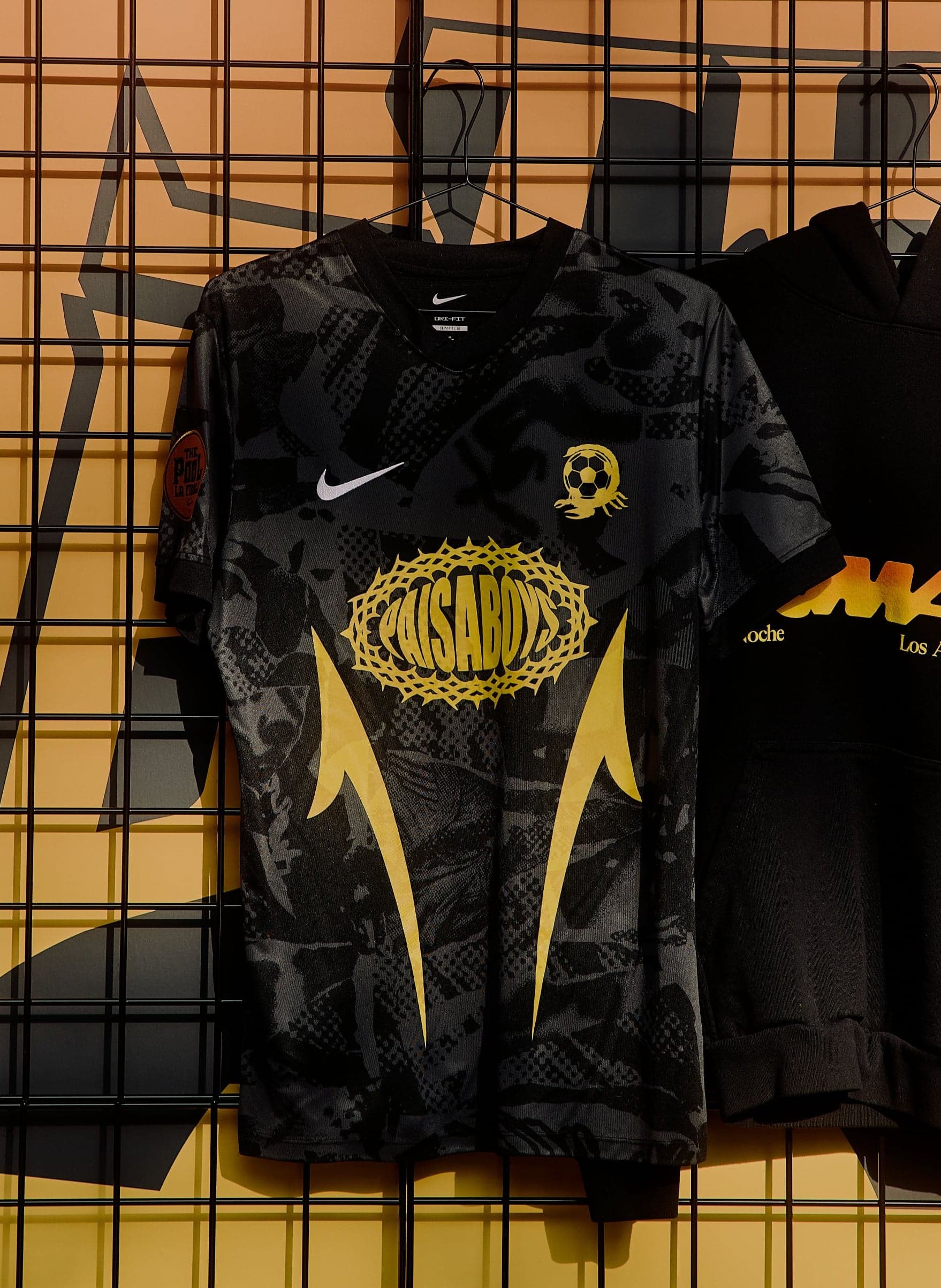 Black TOMA jerseys hanging on a grid wall