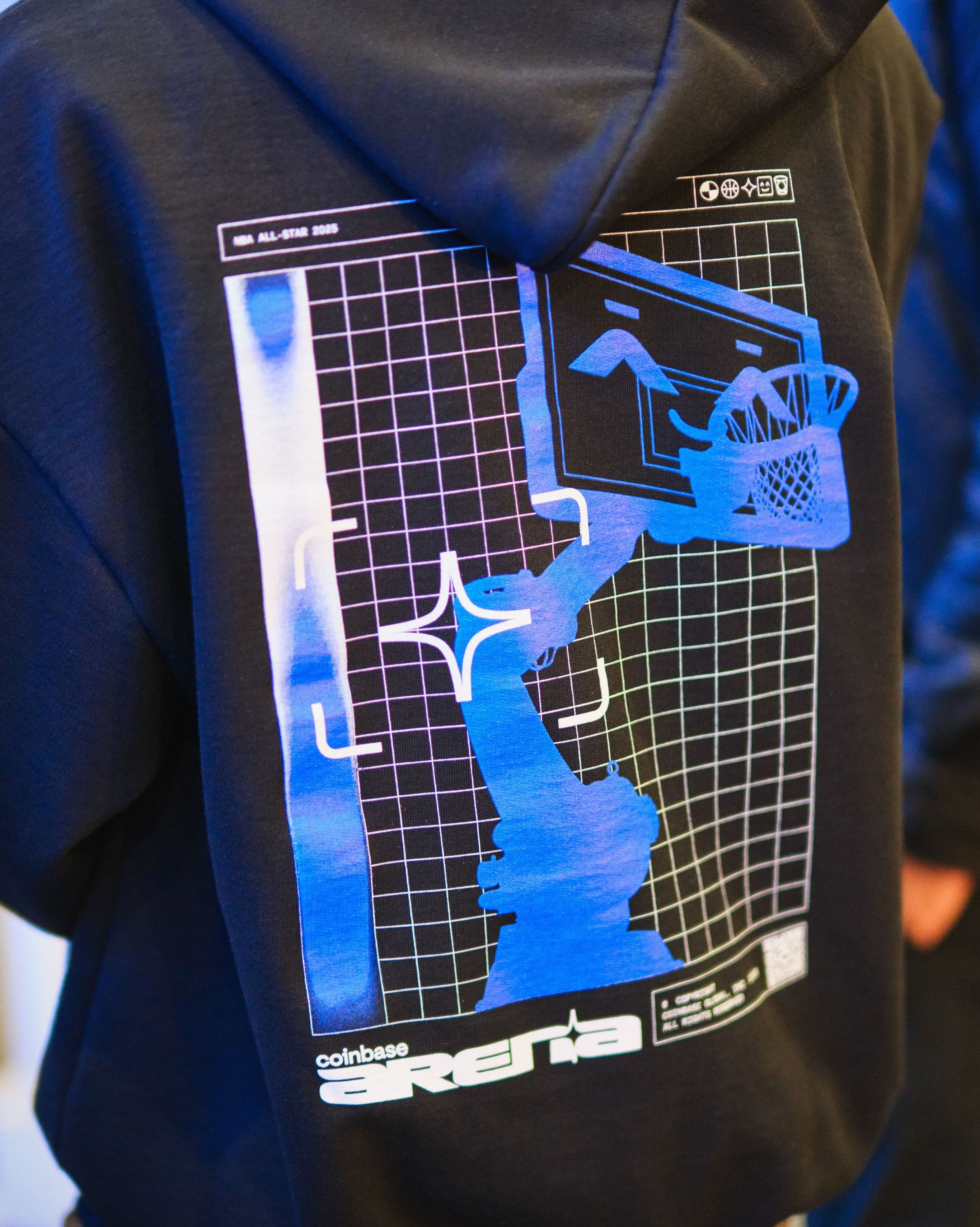 The back of a black hoodie printed with the Coinbase Arena robo-hoop graphic