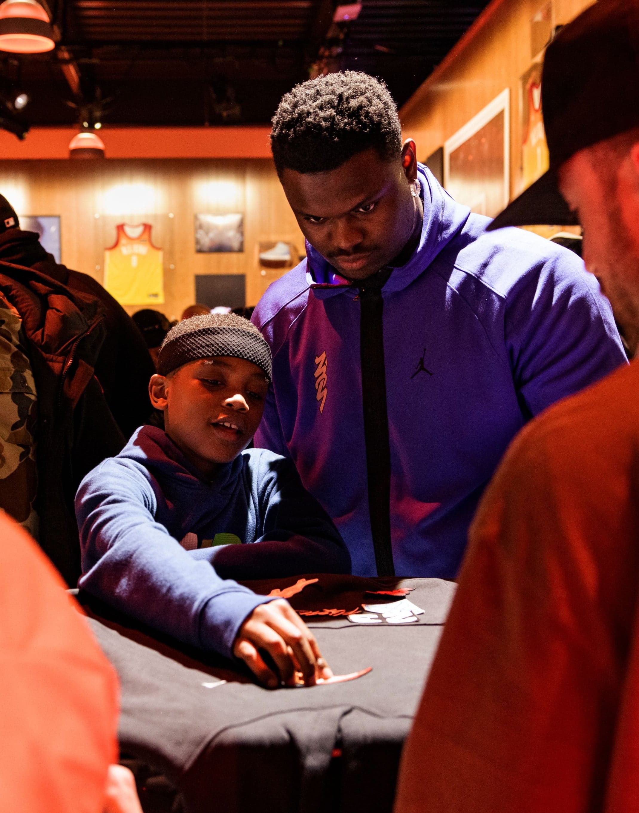 A young fan and others customizing a black garment at a table
