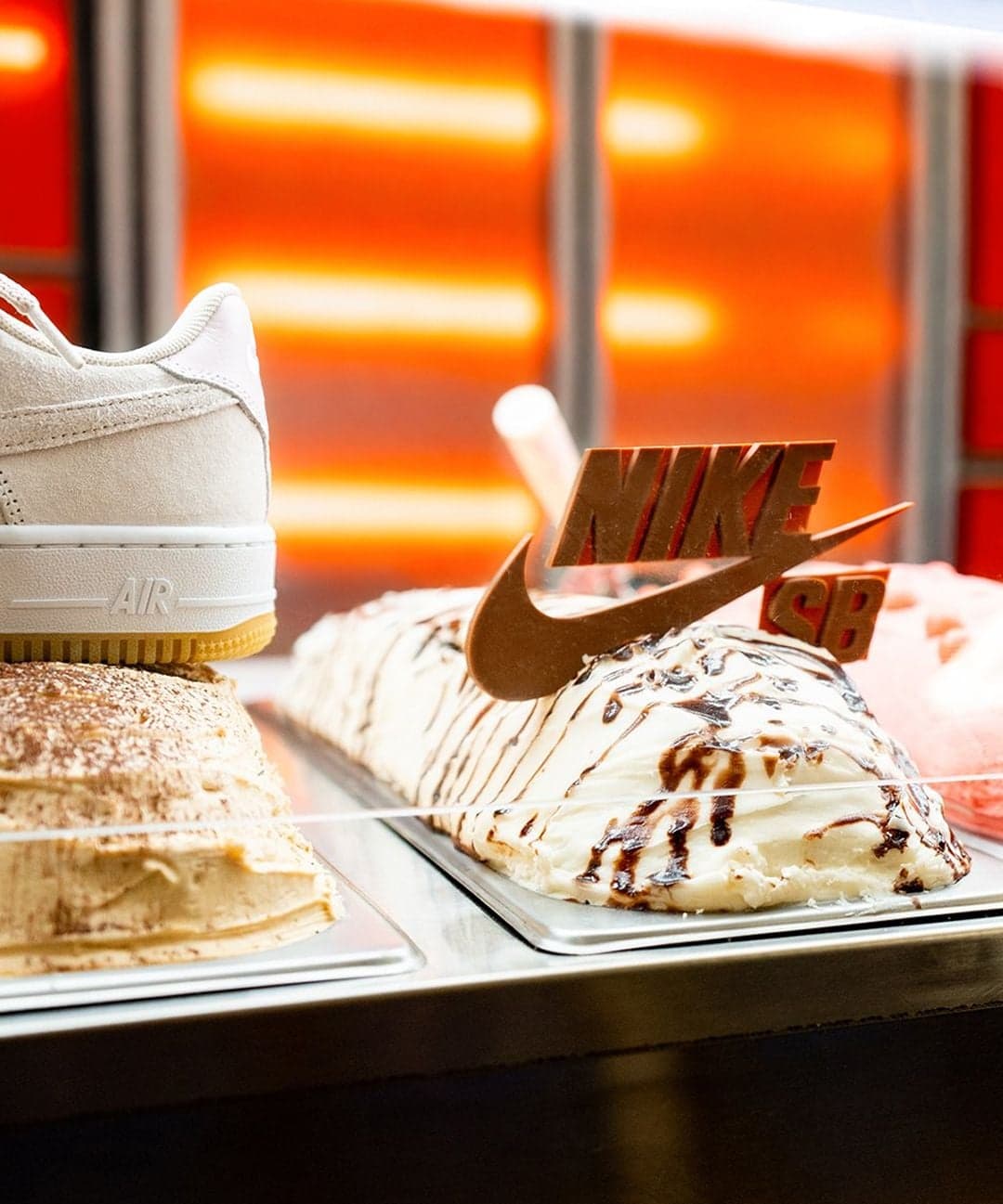 A white sneaker beside a dessert topped with a chocolate Nike swoosh