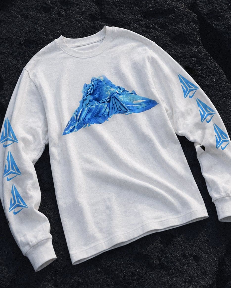 A white long-sleeve tee with an ice sneaker graphic, laid on dark rock