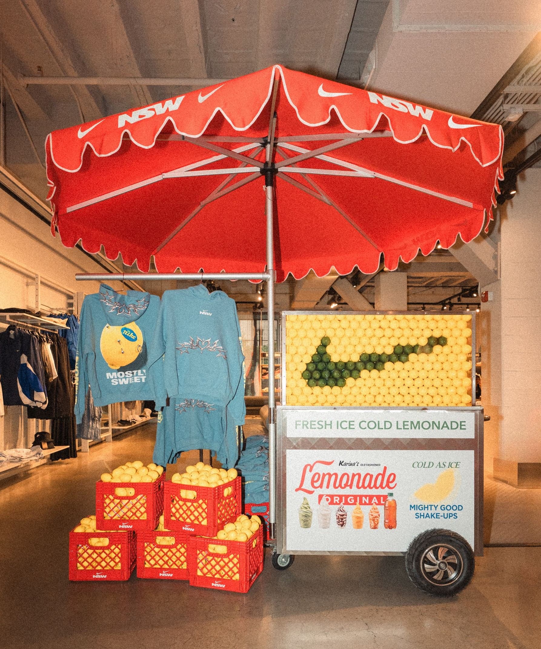 The finished lemonade cart in the store, under a red scalloped umbrella with crates of lemons