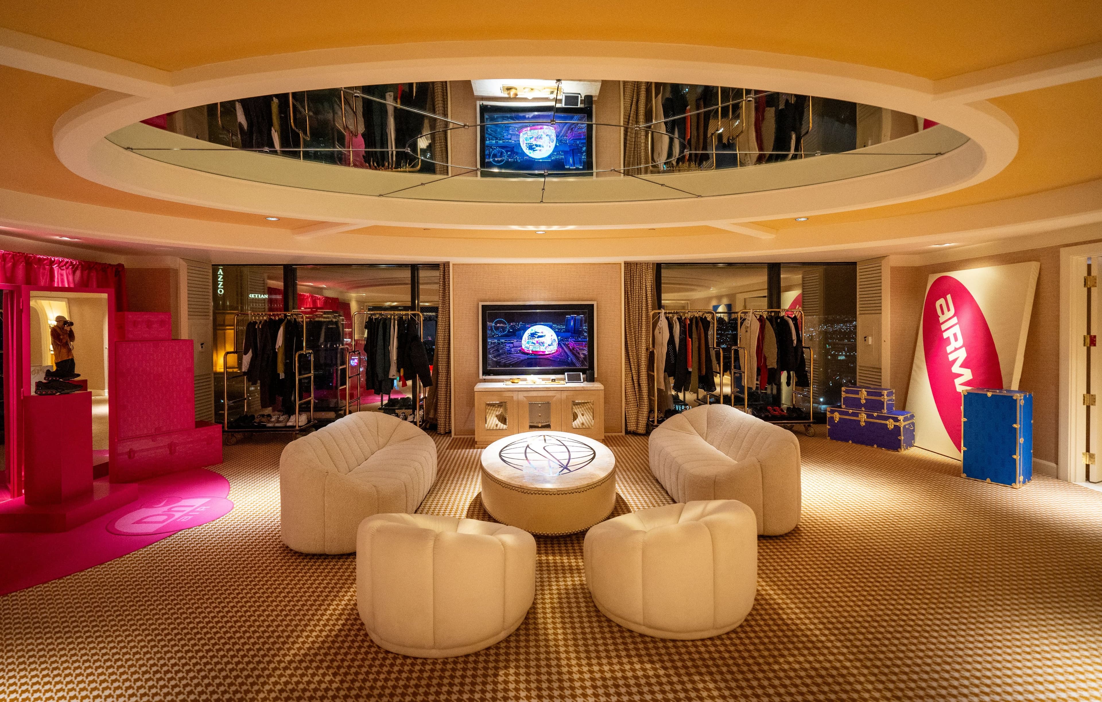 The penthouse lounge: white armchairs around a round table under a mirrored ceiling, with clothing rails and screens behind