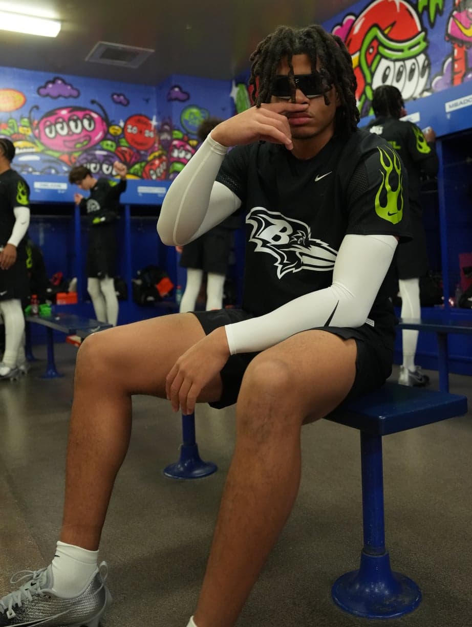 A player in sunglasses sitting on a bench in the muralled locker room