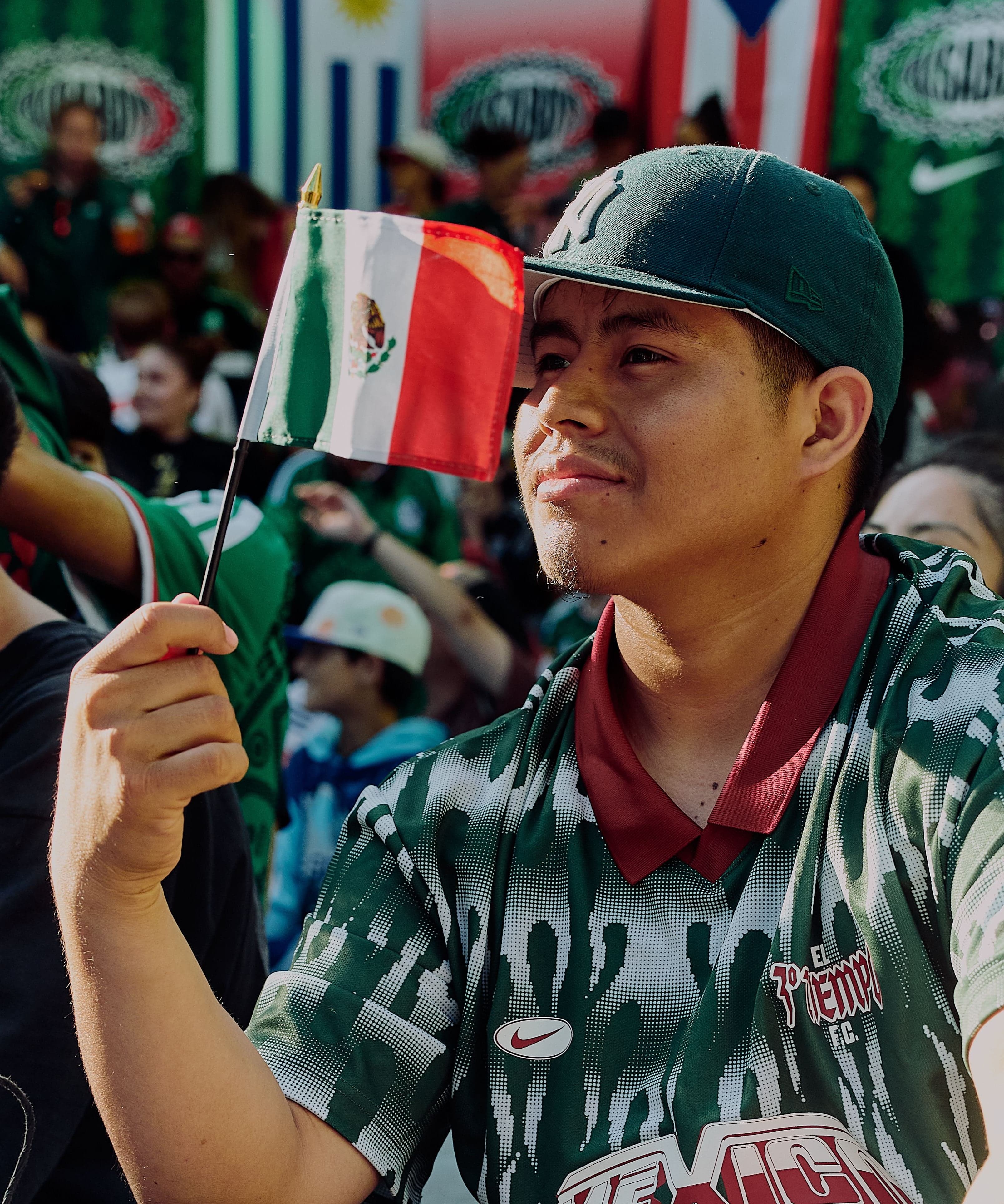 A fan in a Mexico jersey waving a small Mexican flag
