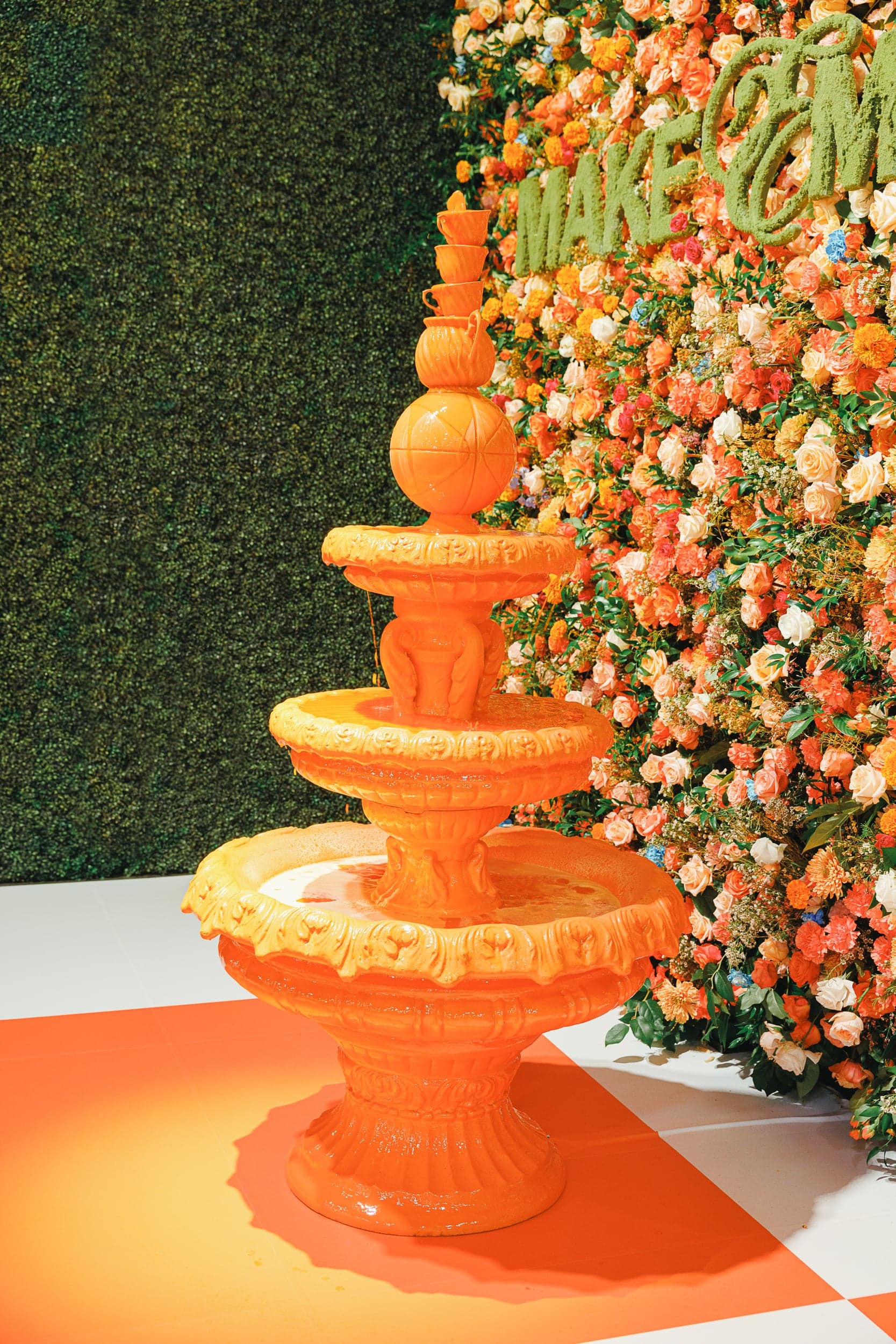 Close-up of the tiered orange fountain against a wall of flowers