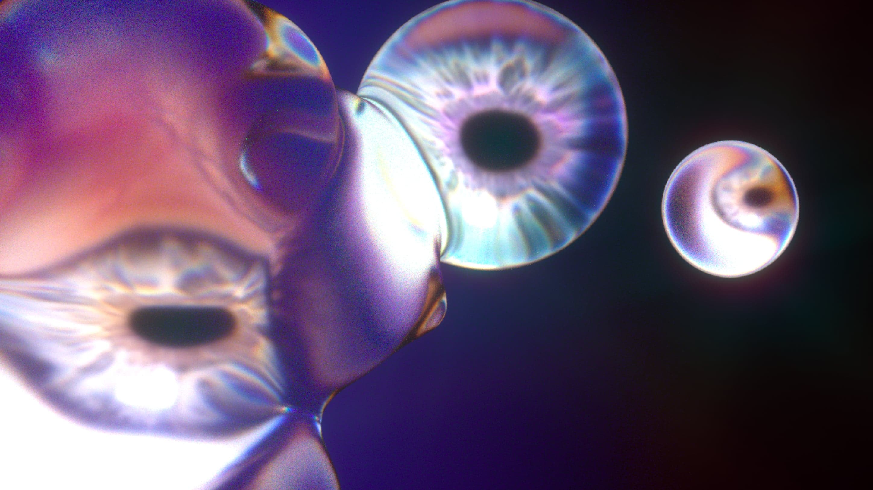 3D renders of iridescent glass eyeballs floating against a dark purple background