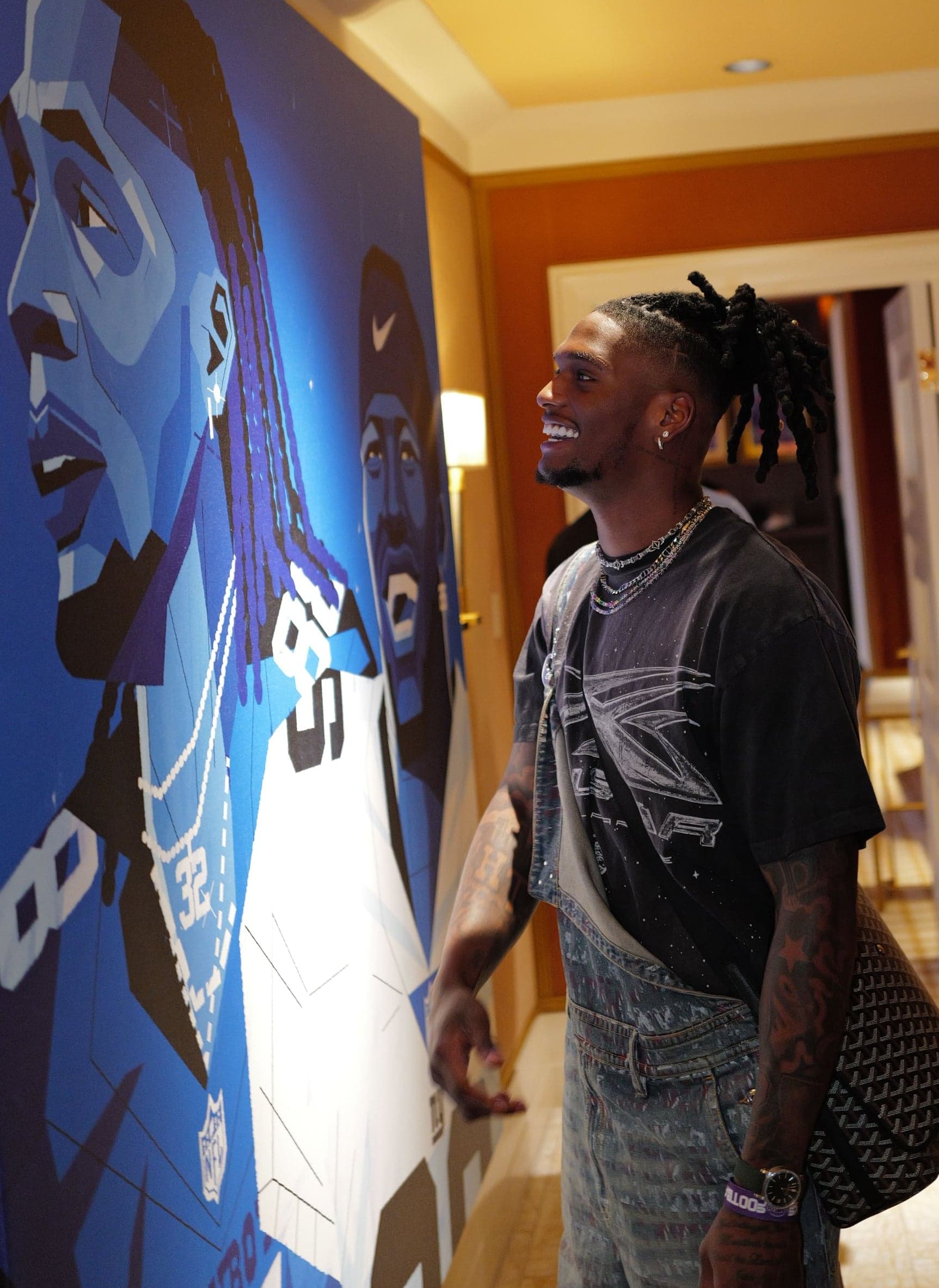 A guest looking up at a large portrait of a Cowboys player in a hotel hallway