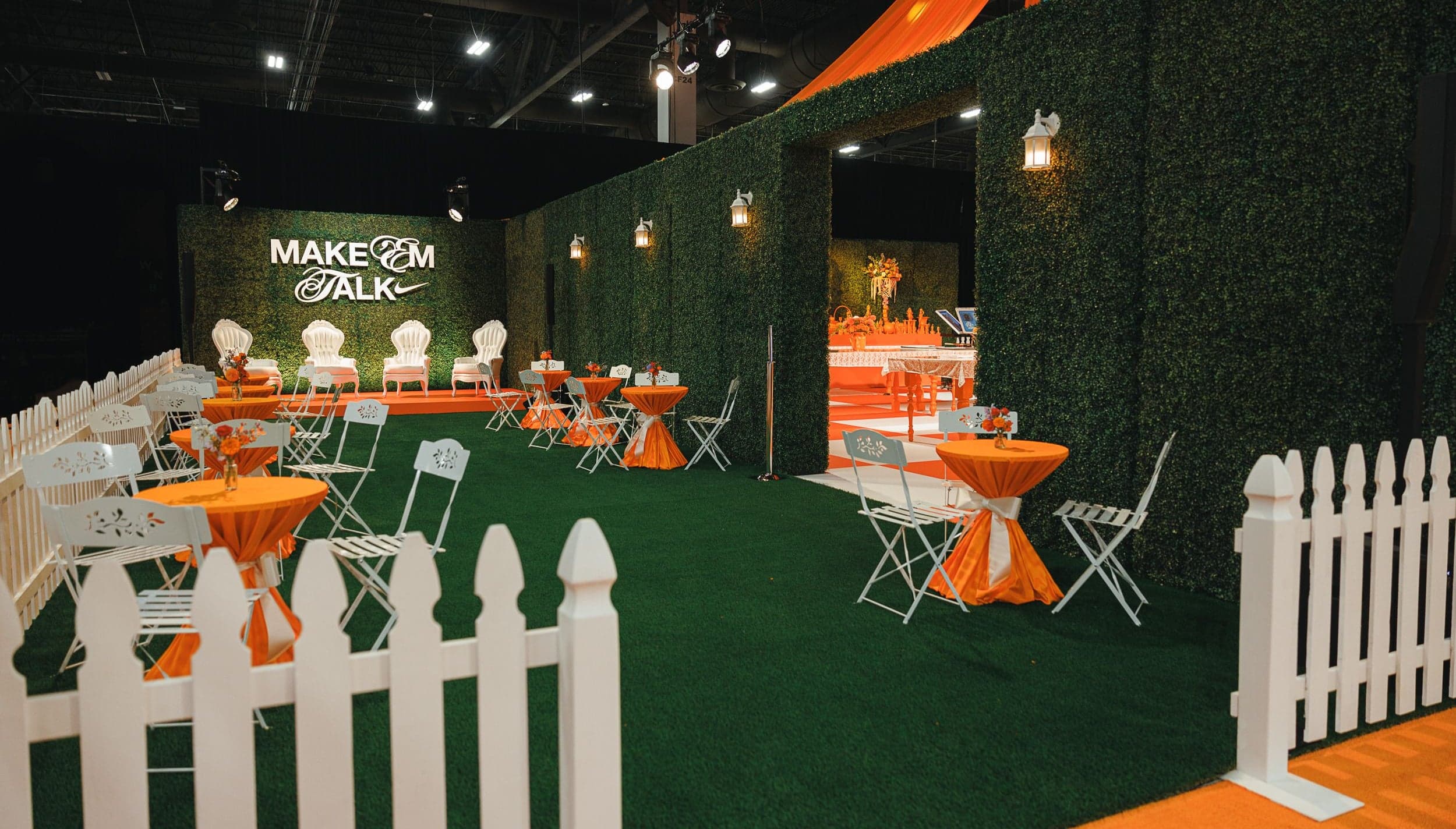 The Make ’Em Talk lounge with bistro tables, turf and white picket fences