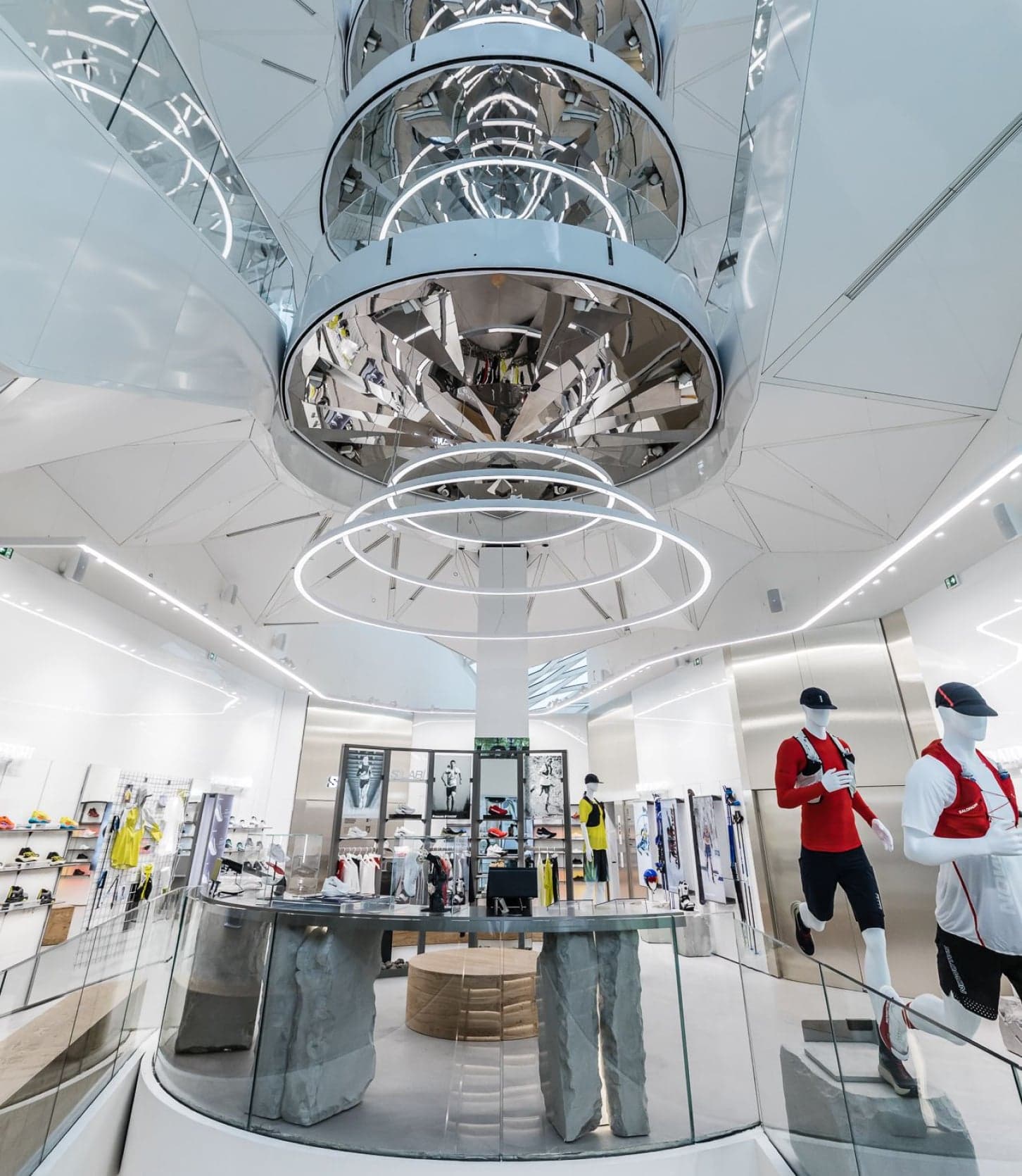 A mirrored, ringed chandelier hanging above the atrium and its displays