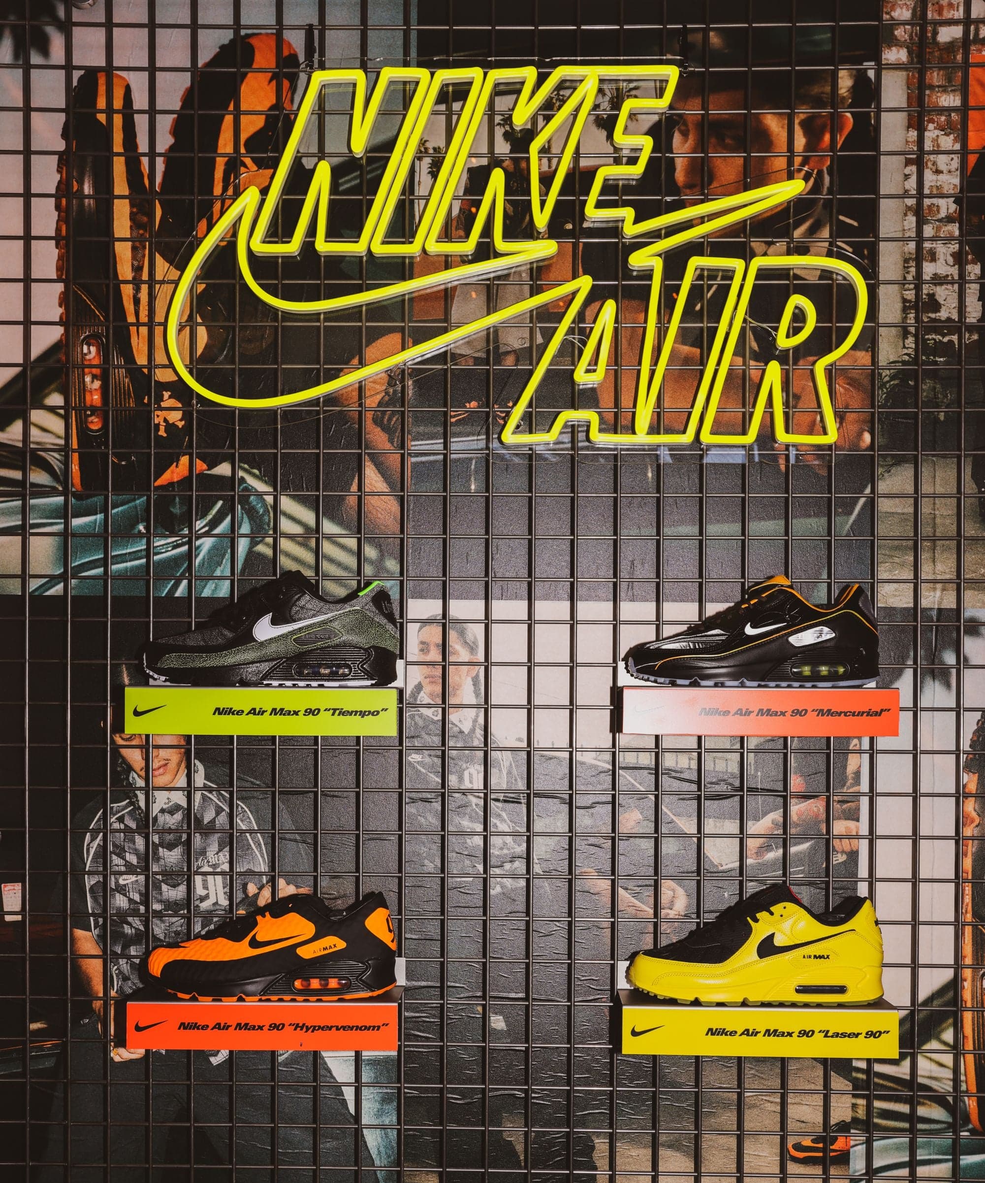 A yellow neon Nike Air sign above sneakers on a mesh wall