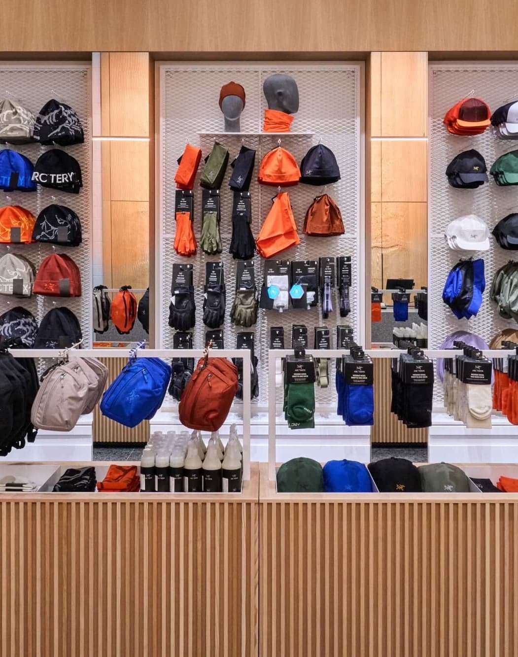 A wood-framed wall of beanies, caps and backpacks