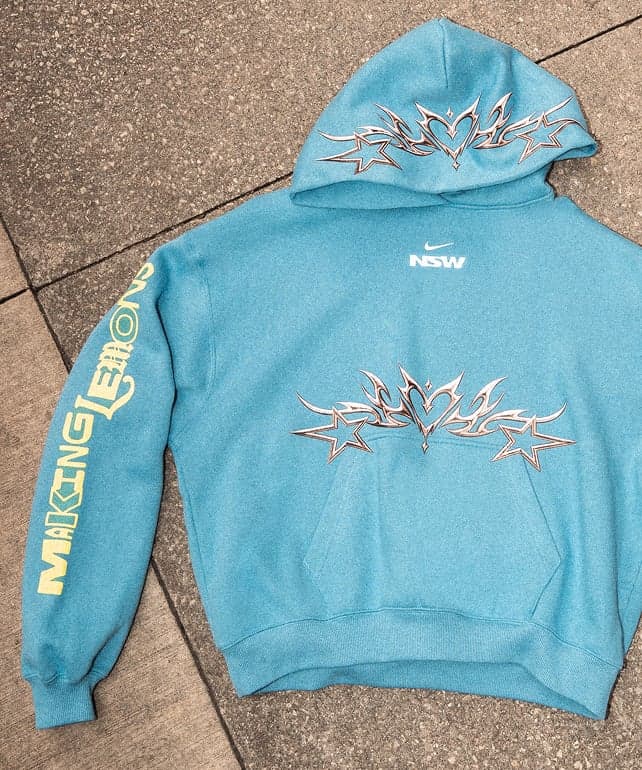 The blue capsule hoodie laid flat, with “Making Lemons” down the sleeve and a chrome graphic on the chest