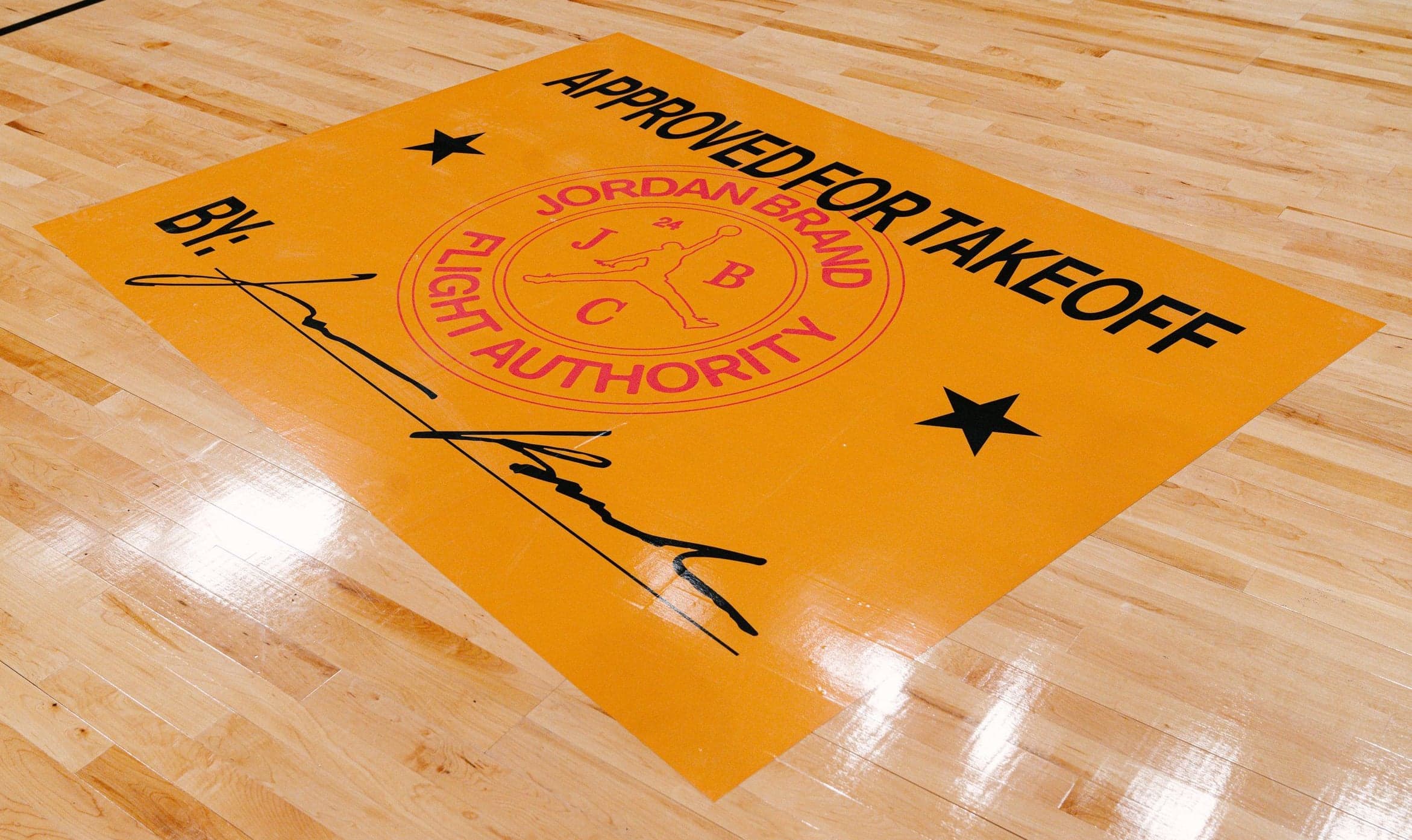 An orange “Approved for Takeoff” Flight Authority graphic on the hardwood court