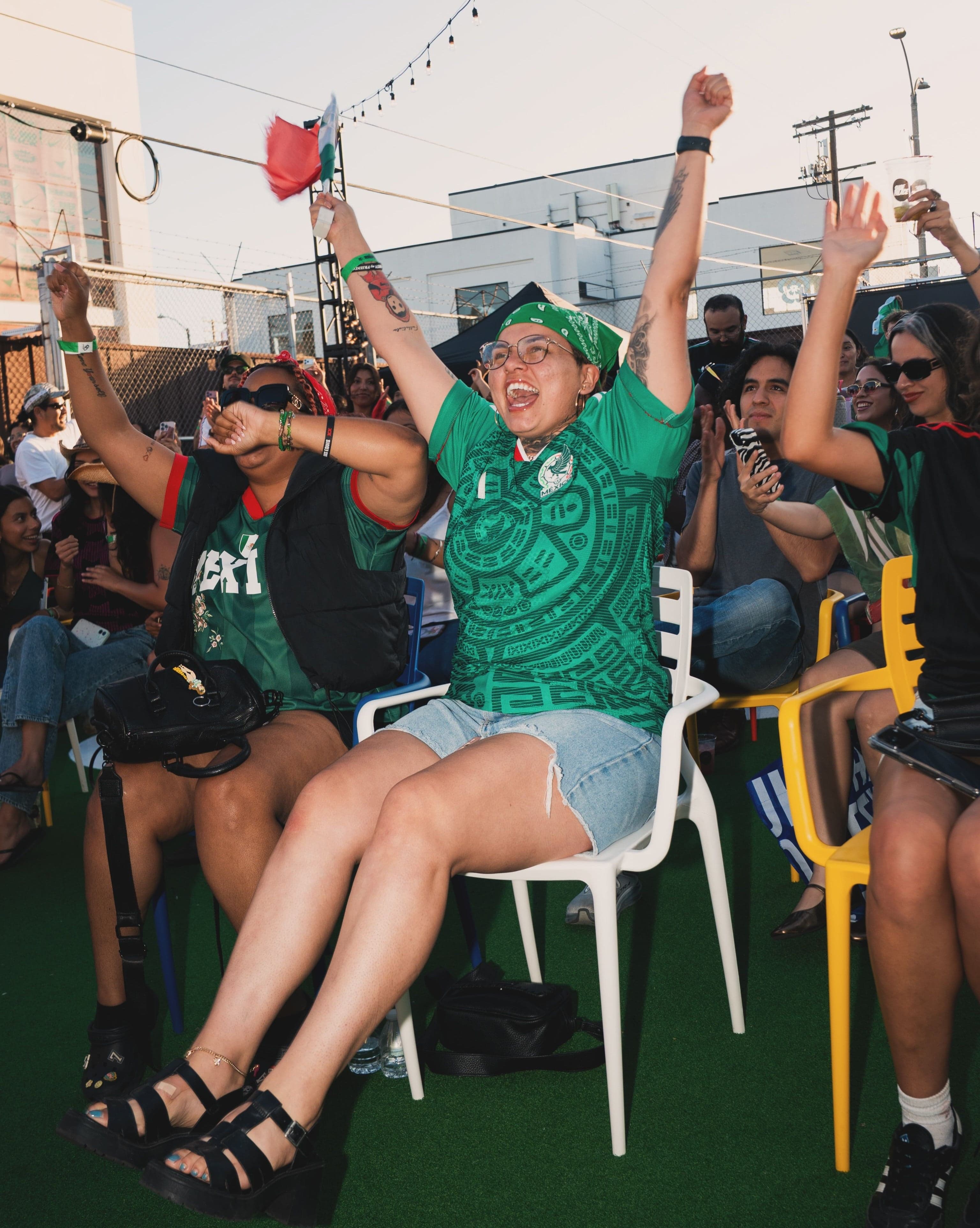 Fans in Mexico jerseys cheering during a match