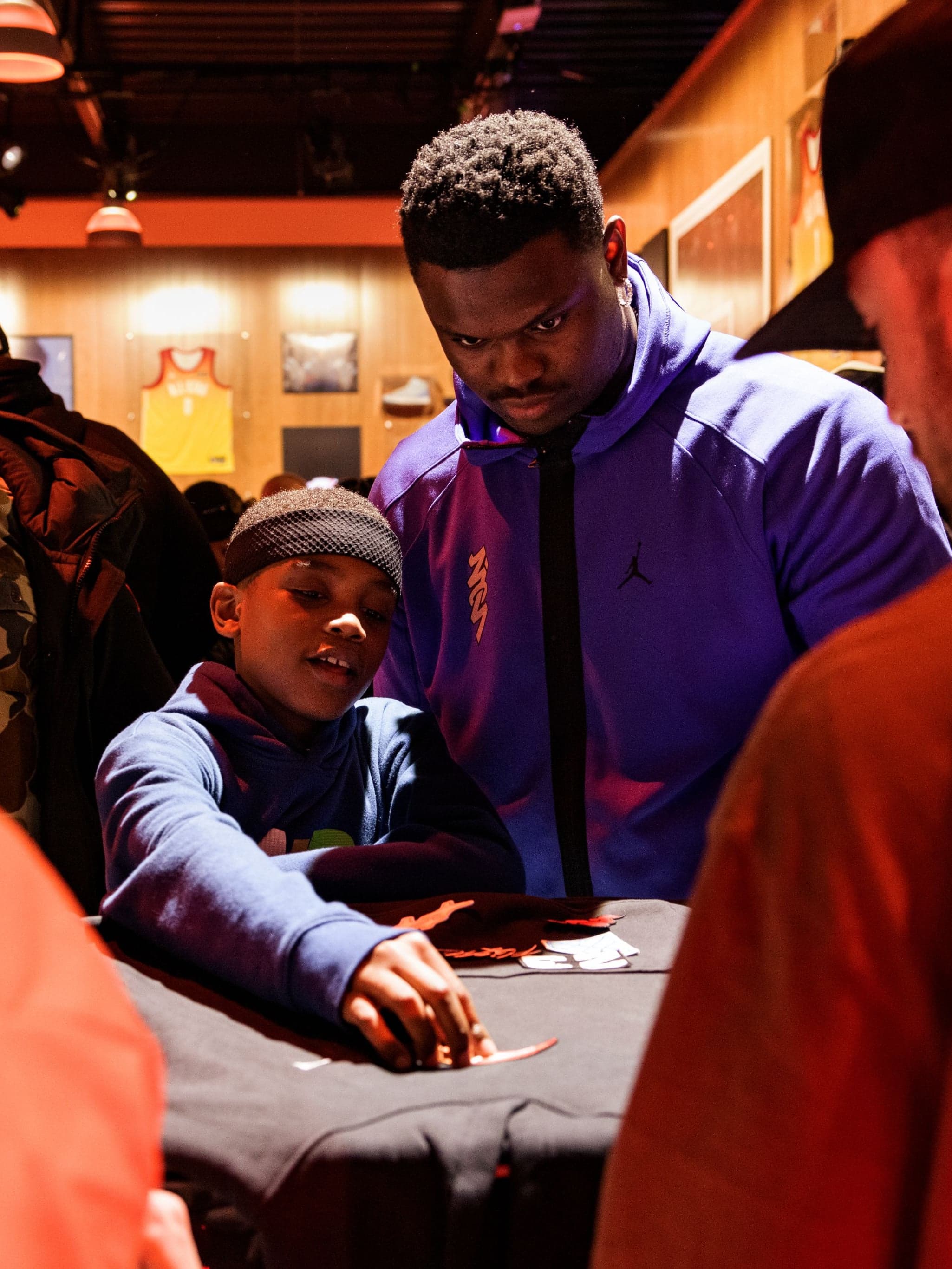 A young fan and others customizing a black garment at a table