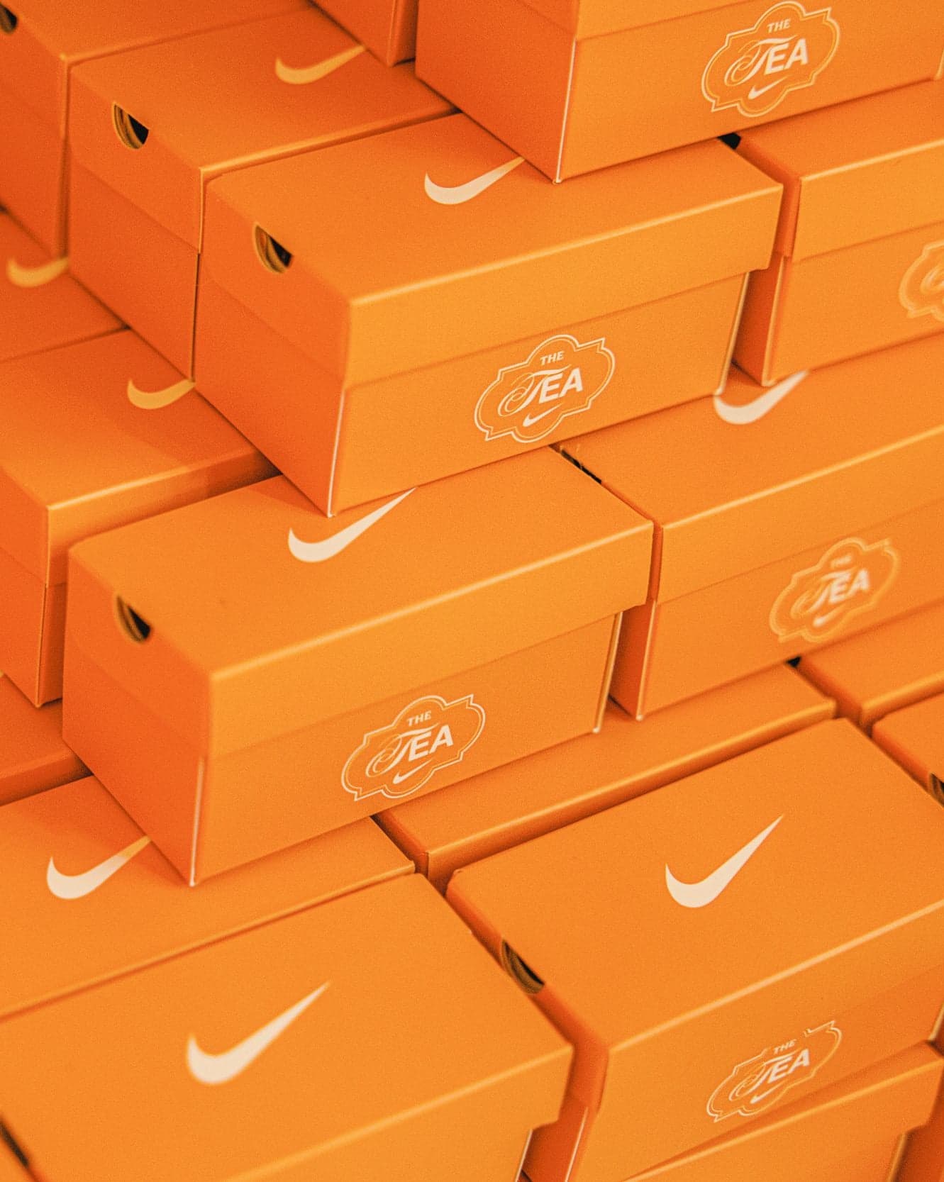 A stack of orange Nike shoeboxes printed with the Tea Garden logo