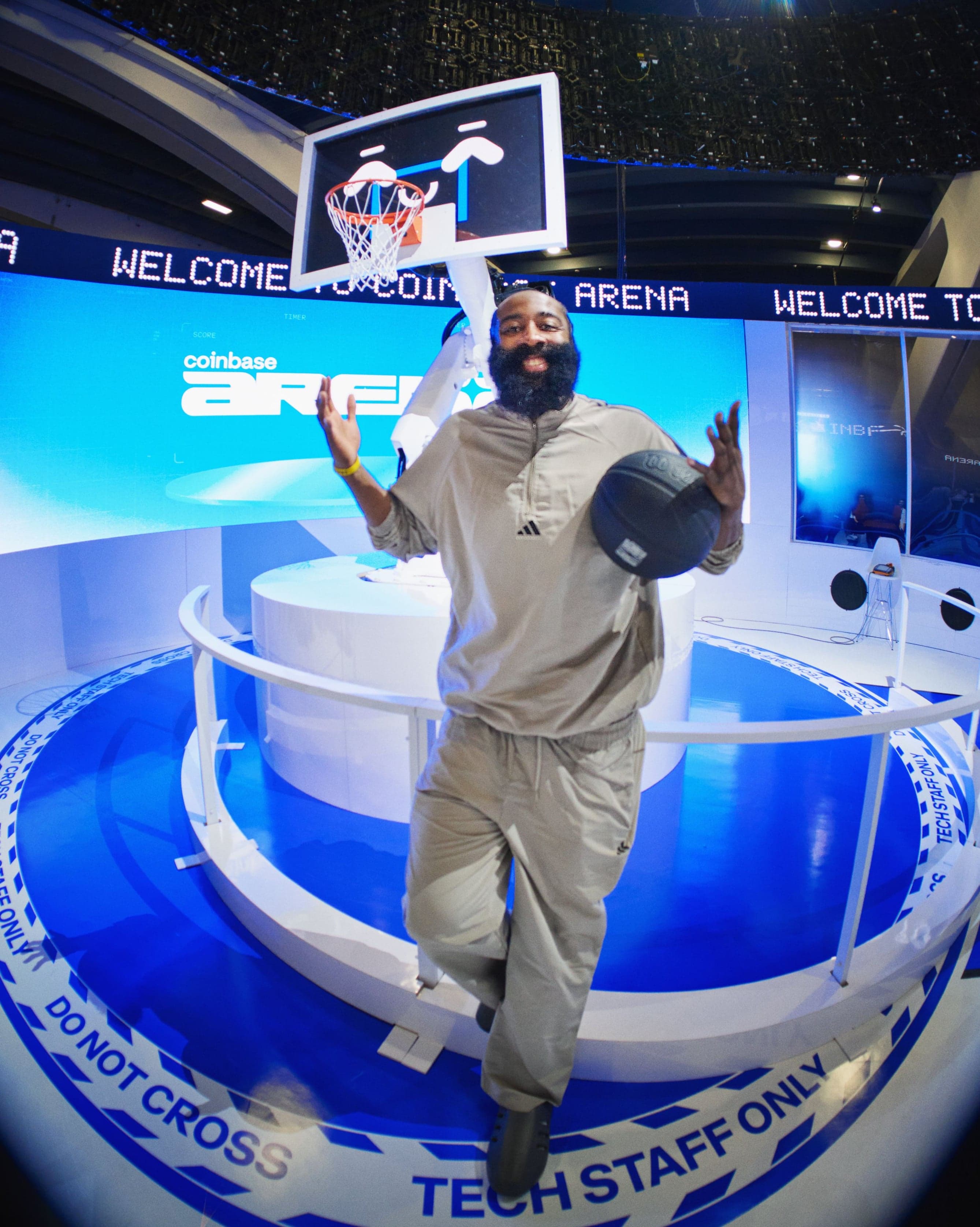 A player in grey poses with a basketball in front of the robotic hoop