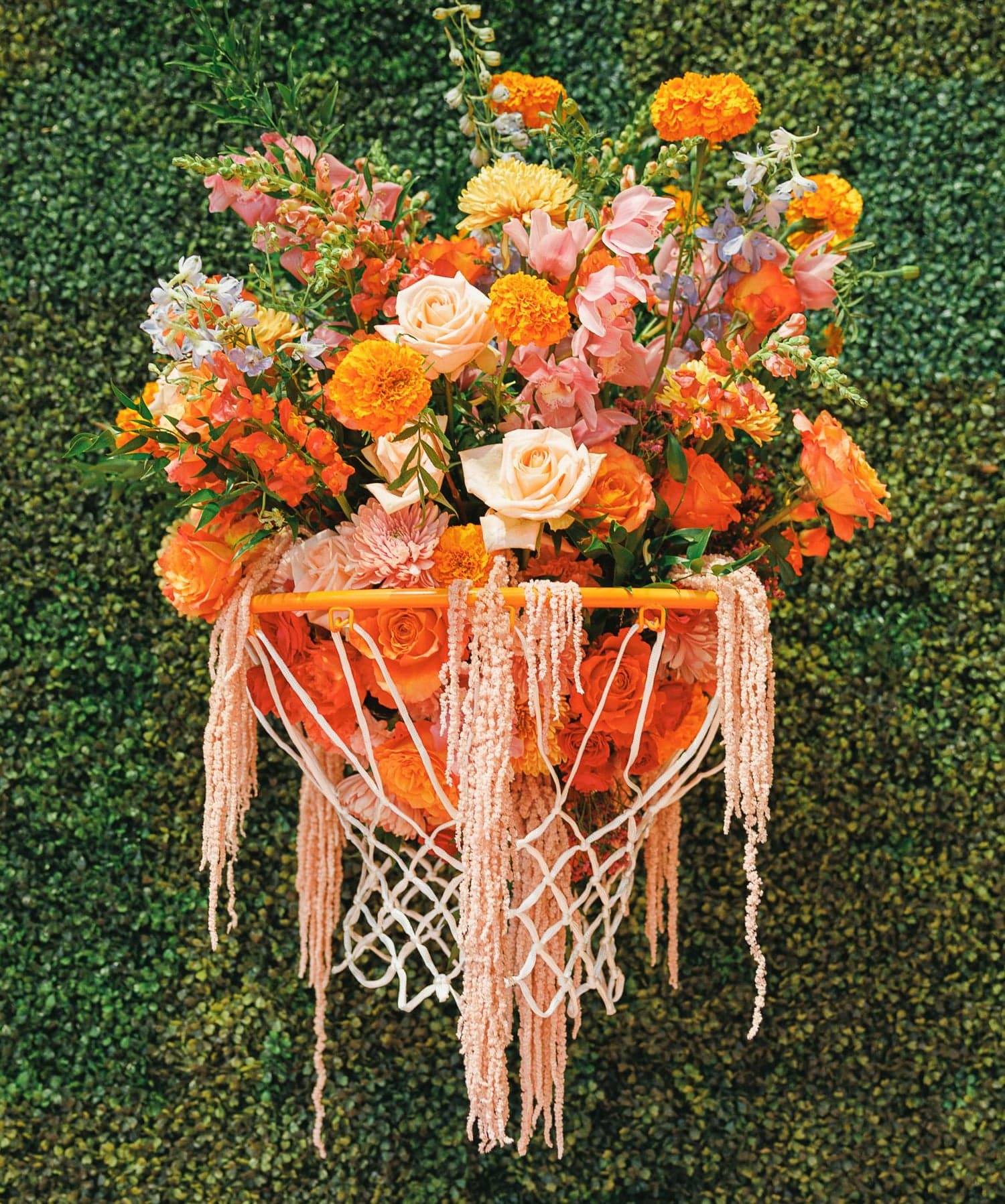 Flowers spilling out of a basketball hoop on a hedge wall